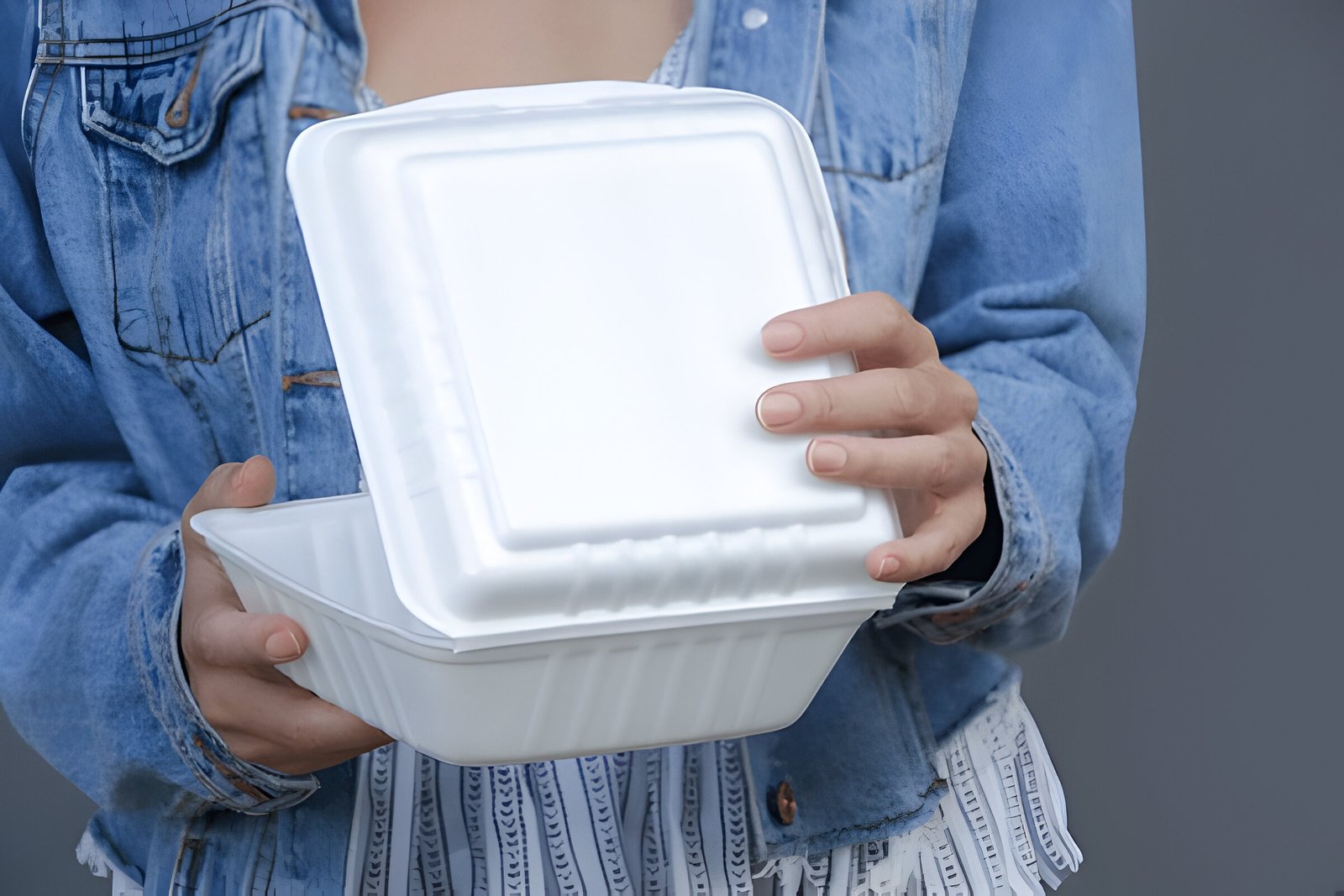 Woman's hands holding takeaway styrofoam container.