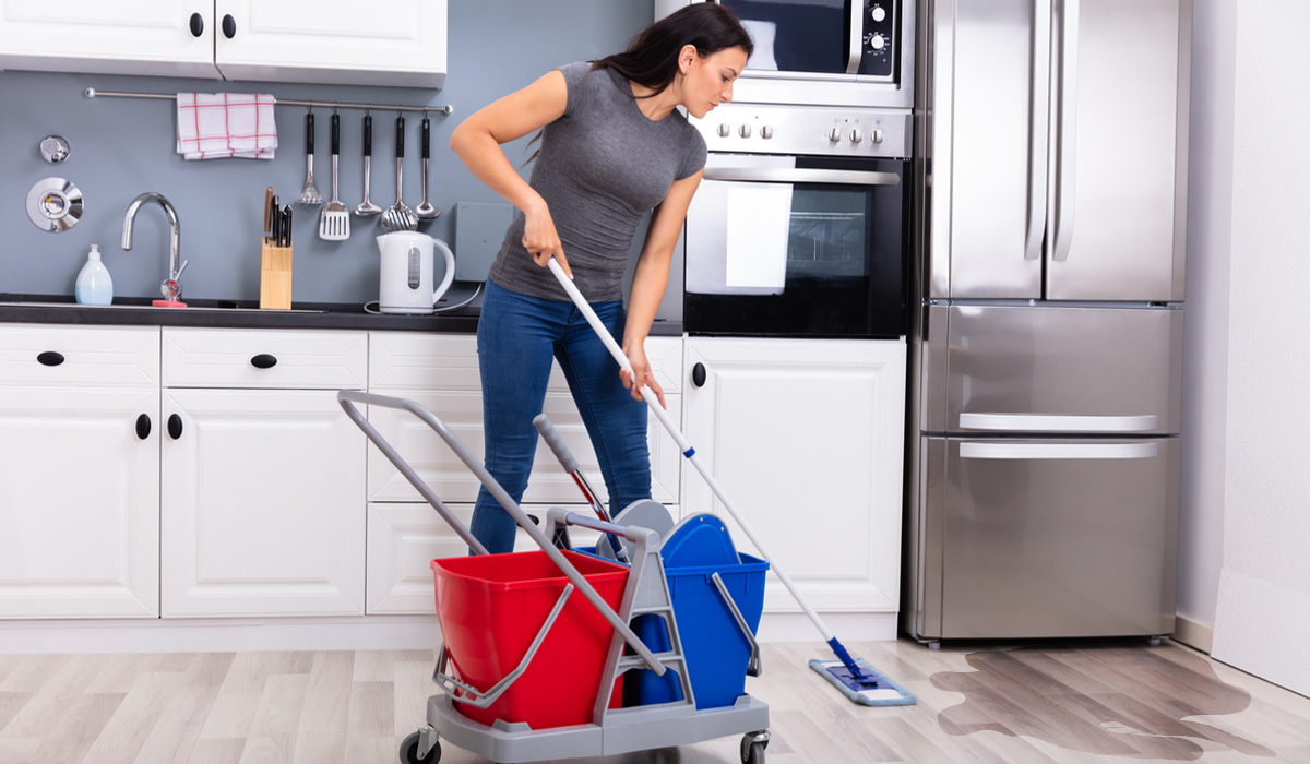 A Woman Cleaning the floor with a Mop in a Kitchen